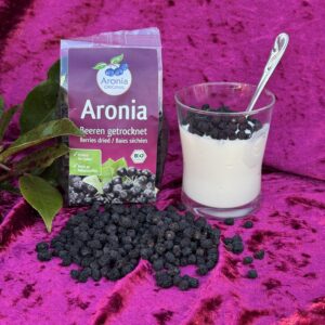 Tørrede aroniabær og yoghurt på pink baggrund