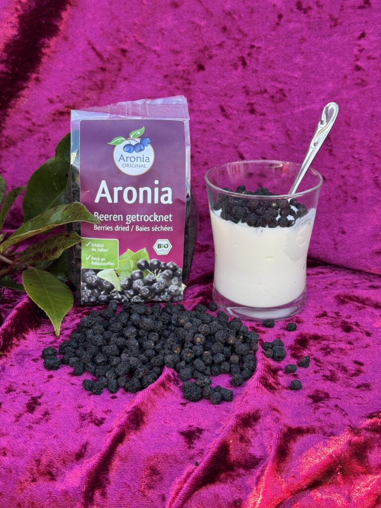 Tørrede aroniabær og yoghurt på pink baggrund