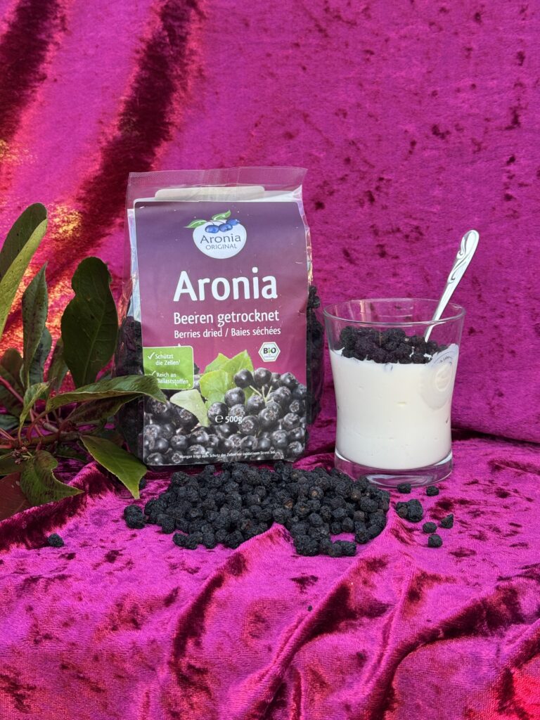 Tørrede aroniabær ved siden af yoghurtglas