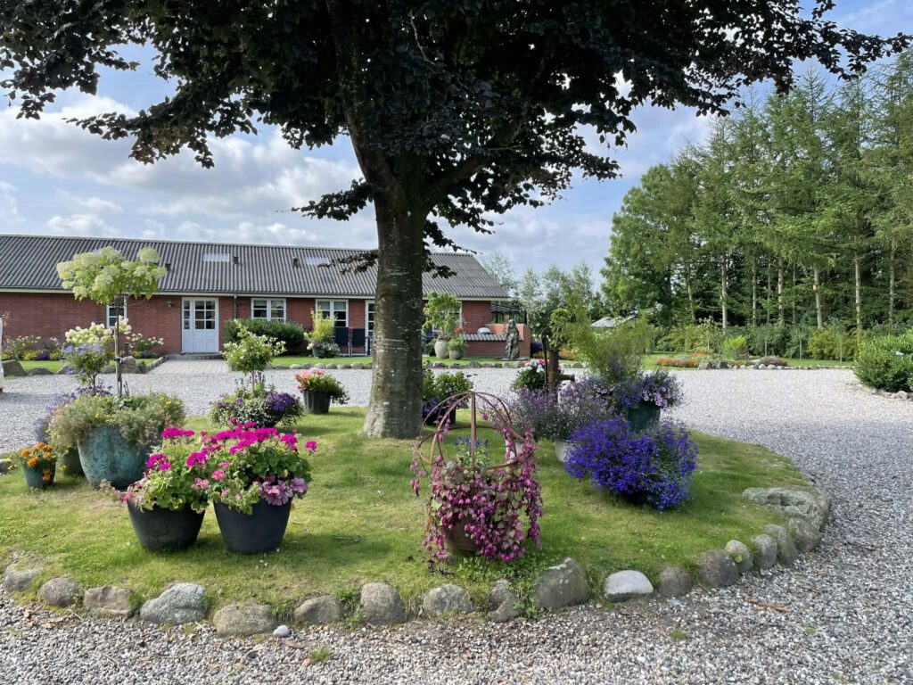 Charmerende gårdhave med blomster og rødt murstenshus